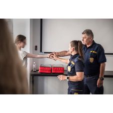 Dwóch funkcjonariuszy demonstruje dziewczynce chwyt w celu obrony