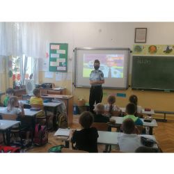 zdjęcie przedstawia klasę z dziećmi oraz strażniczkę miejską prowadzącą zajęcia.
